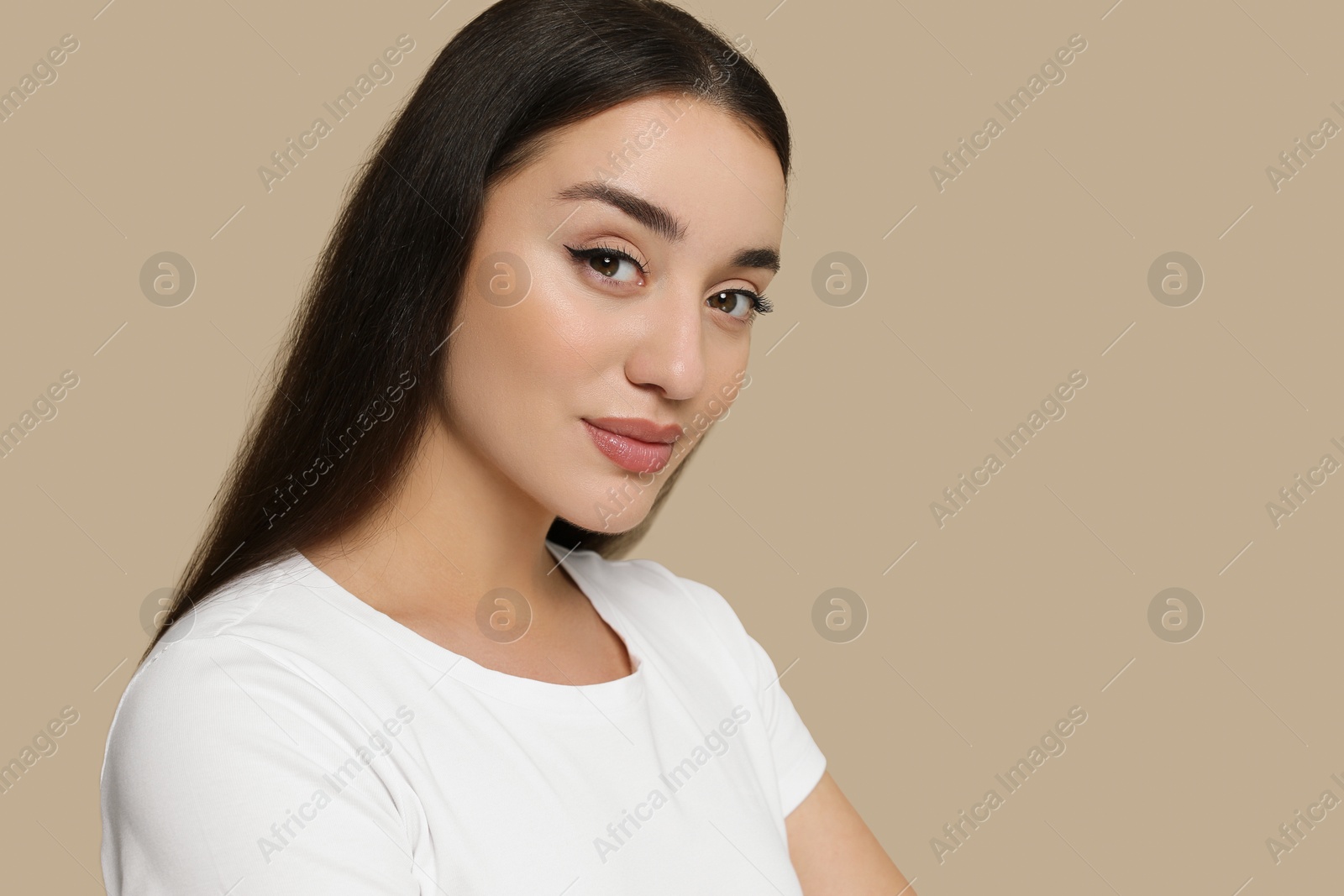 Photo of Portrait of beautiful young woman with elegant makeup on dark beige background. Space for text