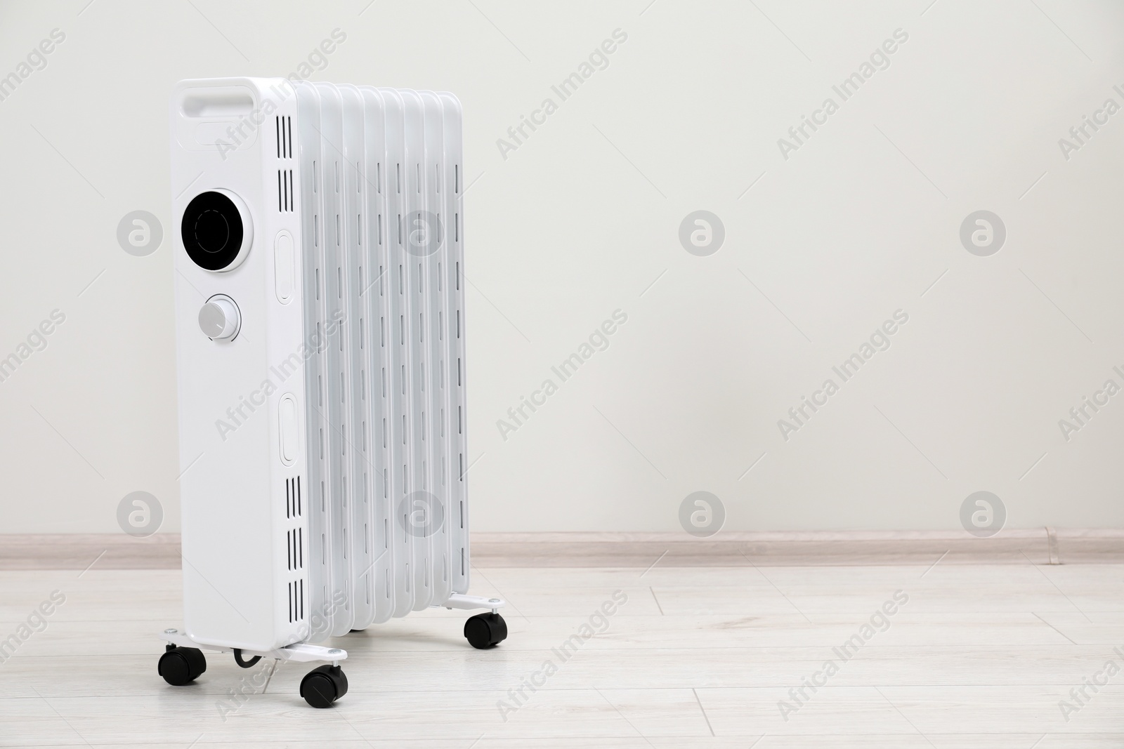 Photo of Modern portable electric heater on floor near white wall indoors, space for text