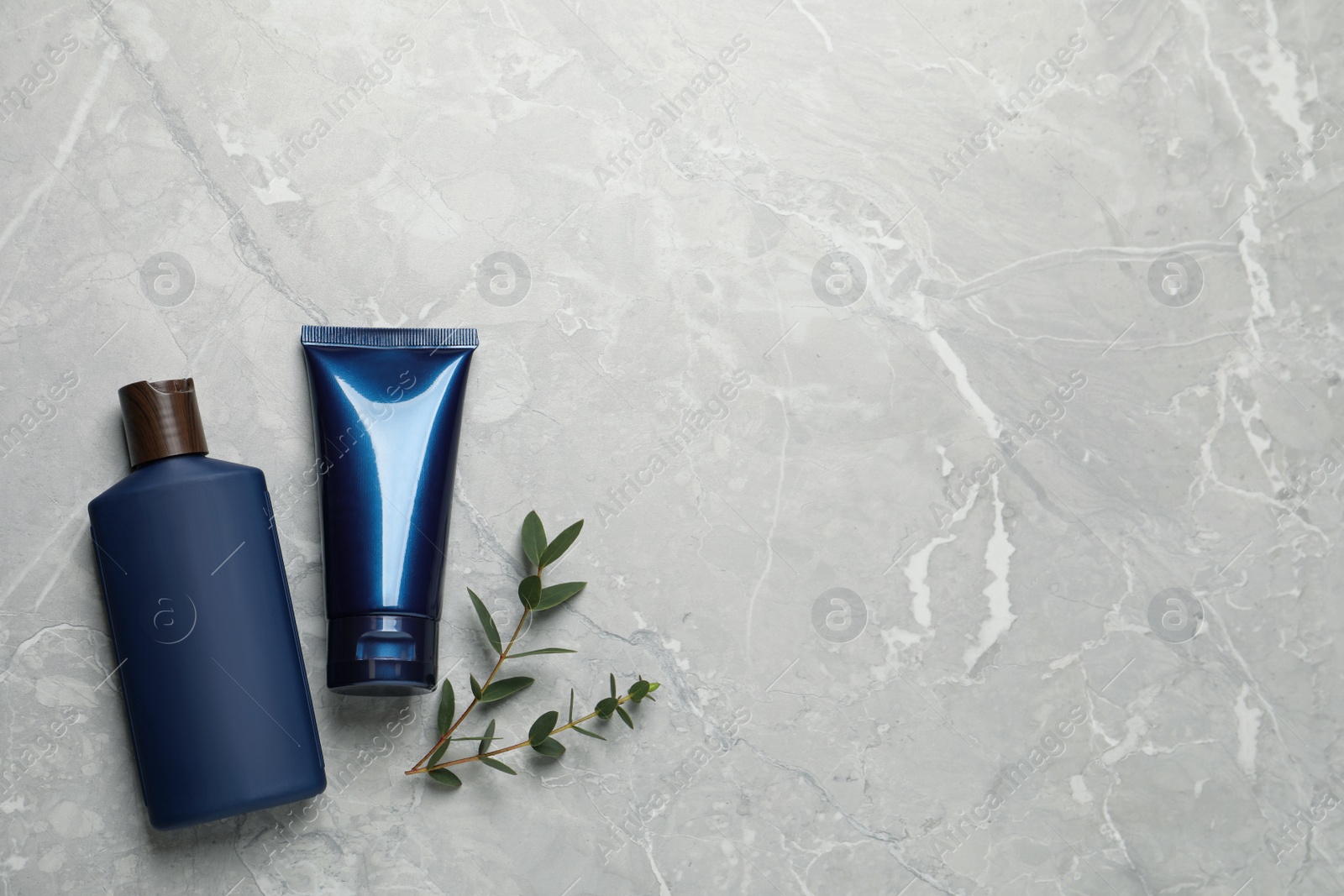 Photo of Men's facial cream, shampoo and green leaves on light grey marble table, flat lay. Mockup for design