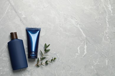 Men's facial cream, shampoo and green leaves on light grey marble table, flat lay. Mockup for design