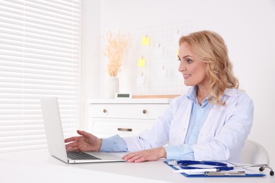Photo of Doctor with laptop consulting patient in clinic. Online medicine concept