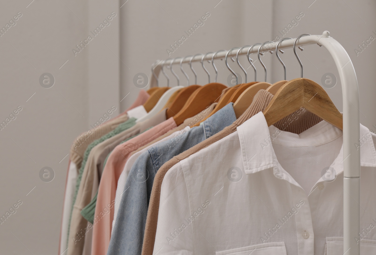 Photo of Rack with stylish clothes near light wall