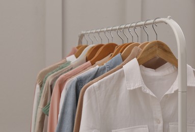 Rack with stylish clothes near light wall