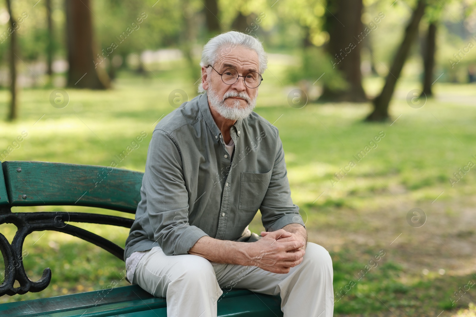 Photo of Portrait of happy grandpa with glasses on bench in park