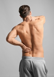 Young man suffering from neck pain on light background