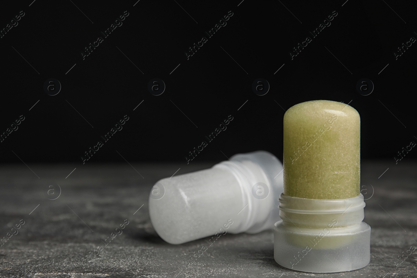 Photo of Natural crystal alum deodorants on grey table against black background