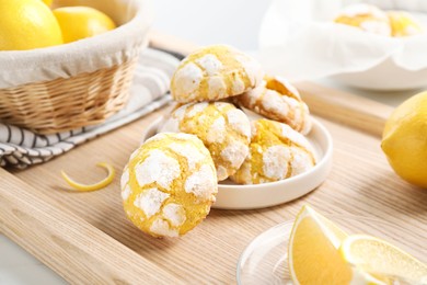 Photo of Tasty homemade lemon cookies and fresh fruits on wooden tray, closeup