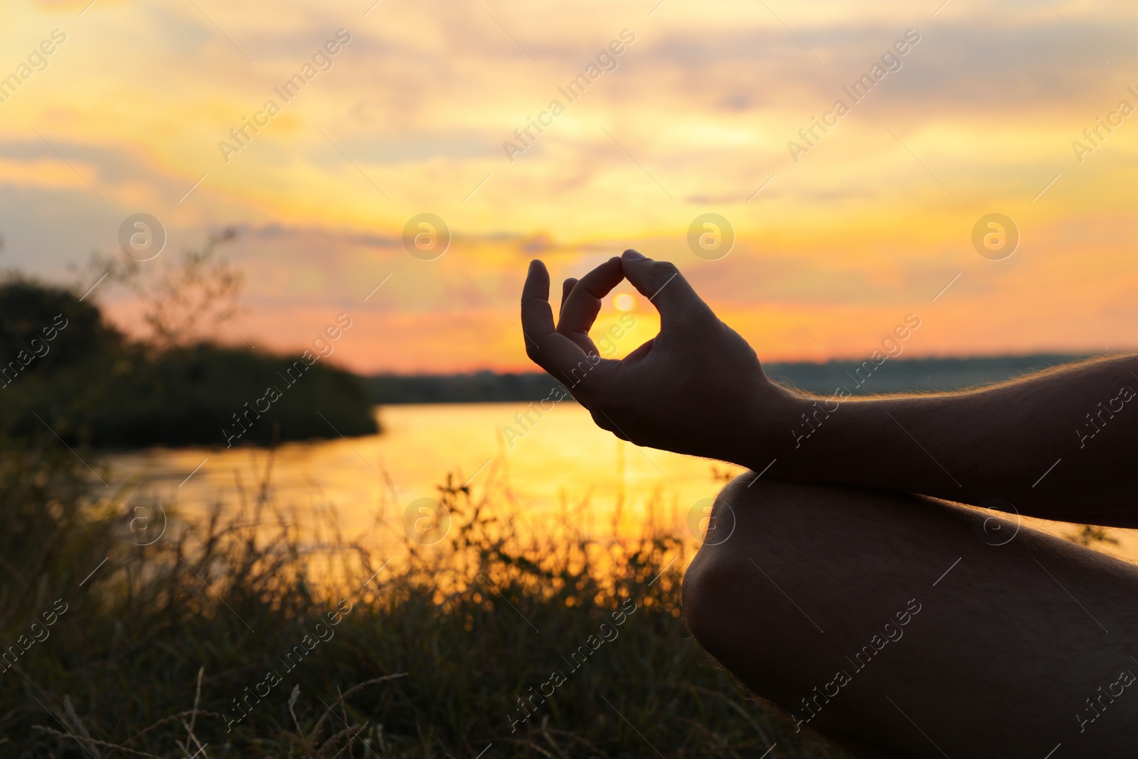 Photo of Man meditating near river at sunset, closeup. Space for text