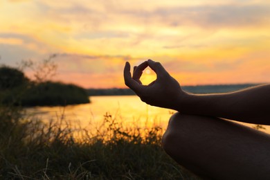 Photo of Man meditating near river at sunset, closeup. Space for text
