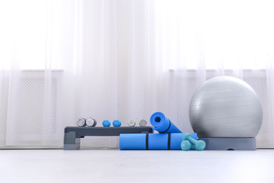 Photo of Different sports equipment near window in gym. Space for text