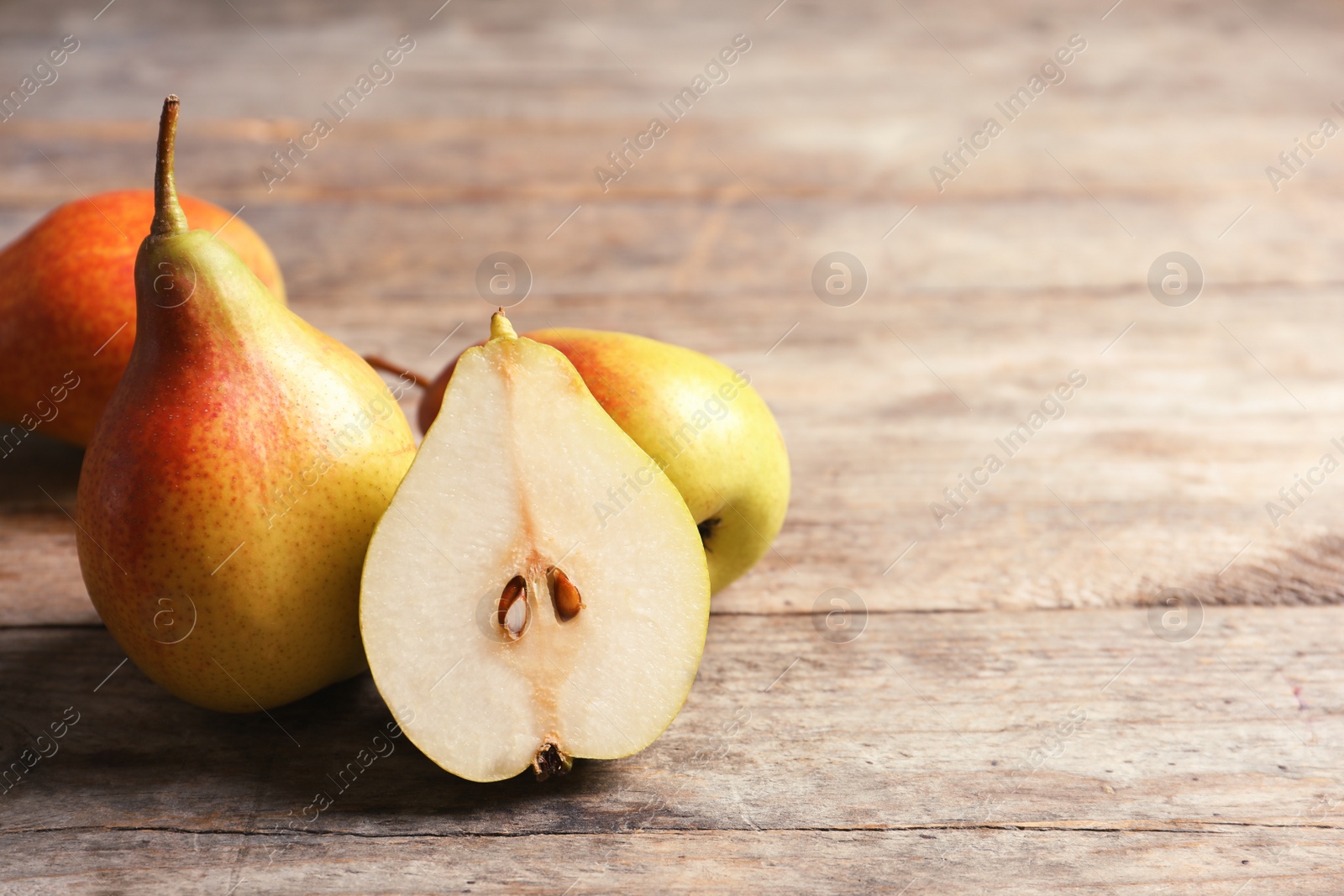 Photo of Ripe pears on wooden table. Space for text