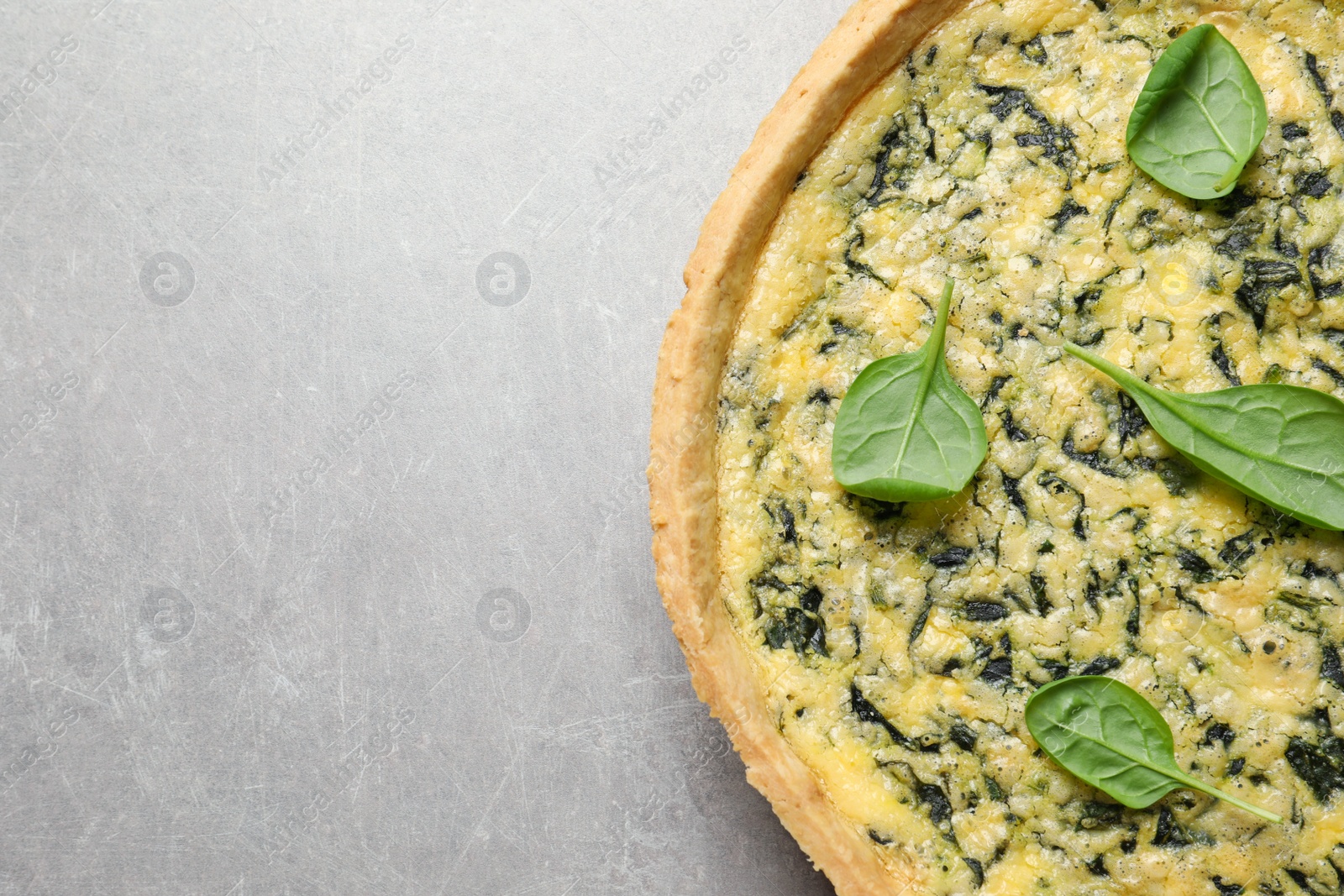 Photo of Delicious homemade spinach pie on light grey table, top view. Space for text