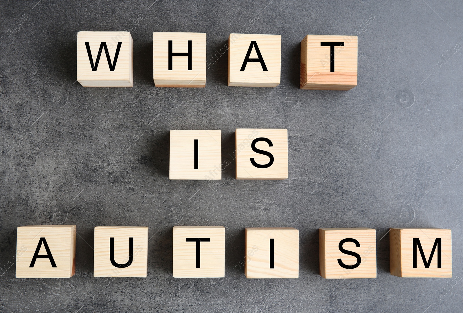 Photo of Wooden cubes with text WHAT IS AUTISM on grey background, top view