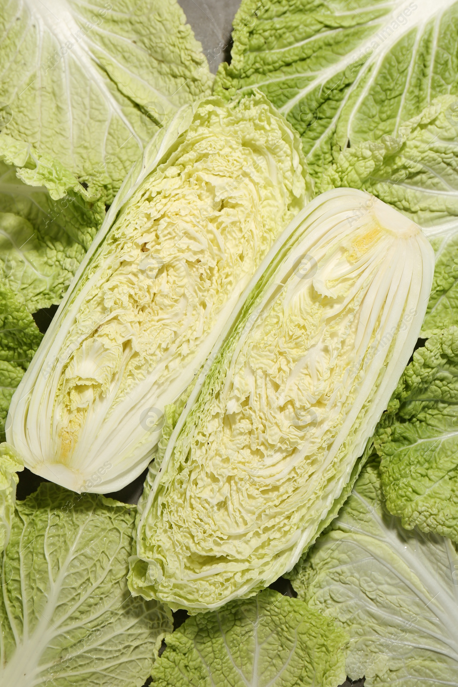 Photo of Halves of fresh Chinese cabbage and green leaves on table, top view