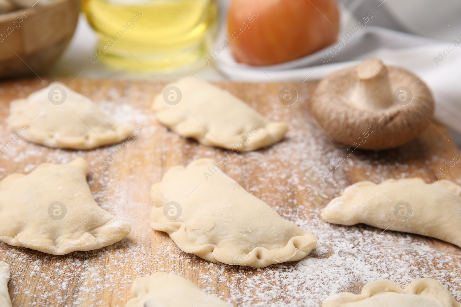 Photo of Raw dumplings (varenyky) with tasty filling on wooden board, closeup. Traditional Ukrainian dish