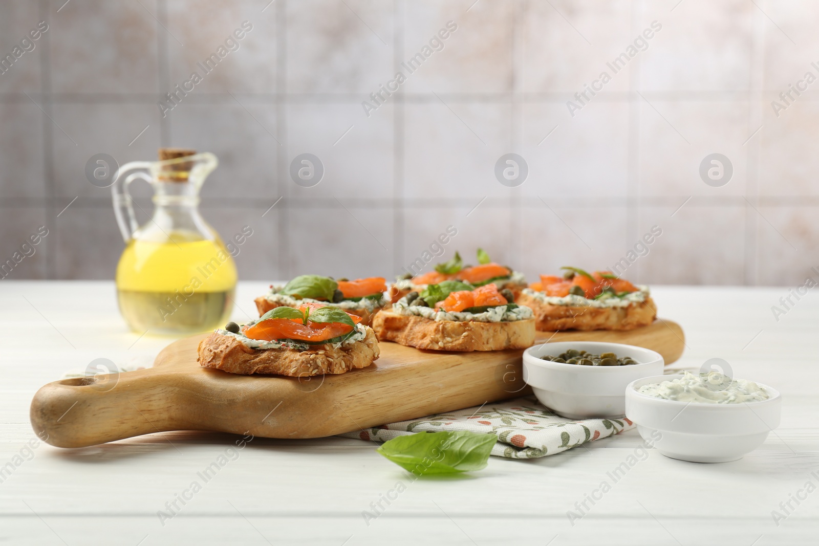 Photo of Tasty canapes with salmon, capers and sauce on white wooden table