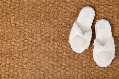 Photo of Door mat and slippers as background, top view. Space for text