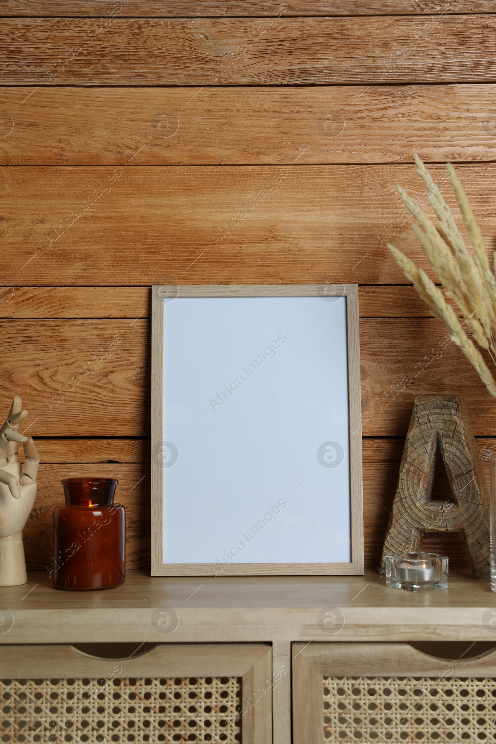 Photo of Empty frame with other decor on table near wooden wall. Mockup for design