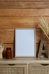 Empty frame with other decor on table near wooden wall. Mockup for design