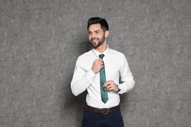 Photo of Portrait of businessman straightening tie on grey background