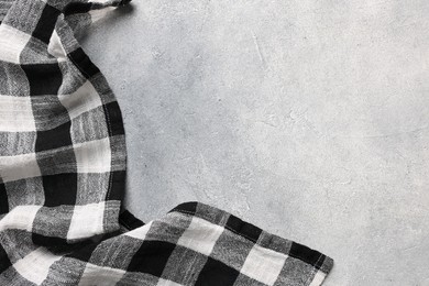 Photo of Black checkered tablecloth on light gray textured table, top view. Space for text