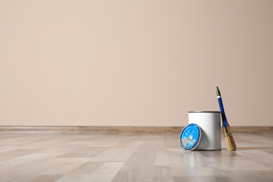 Photo of Can of paint and brush on wooden floor indoors. Space for text
