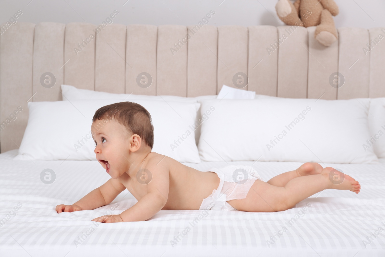 Photo of Cute baby in dry soft diaper on white bed at home
