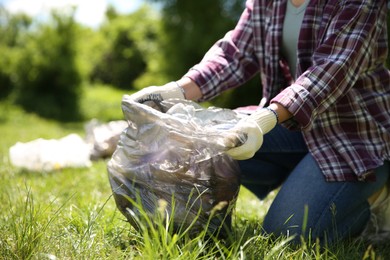 Photo of Woman with plastic bags collecting garbage in park