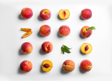 Photo of Fresh ripe peaches and green leaves on white background, flat lay