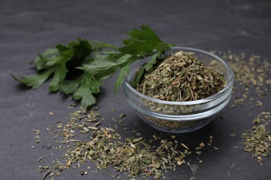 Dried parsley and fresh leaves on black table, closeup