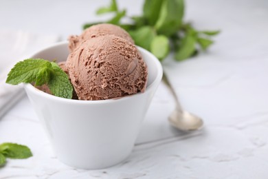 Bowl with tasty chocolate ice cream and mint leaves on white table, closeup. Space for text