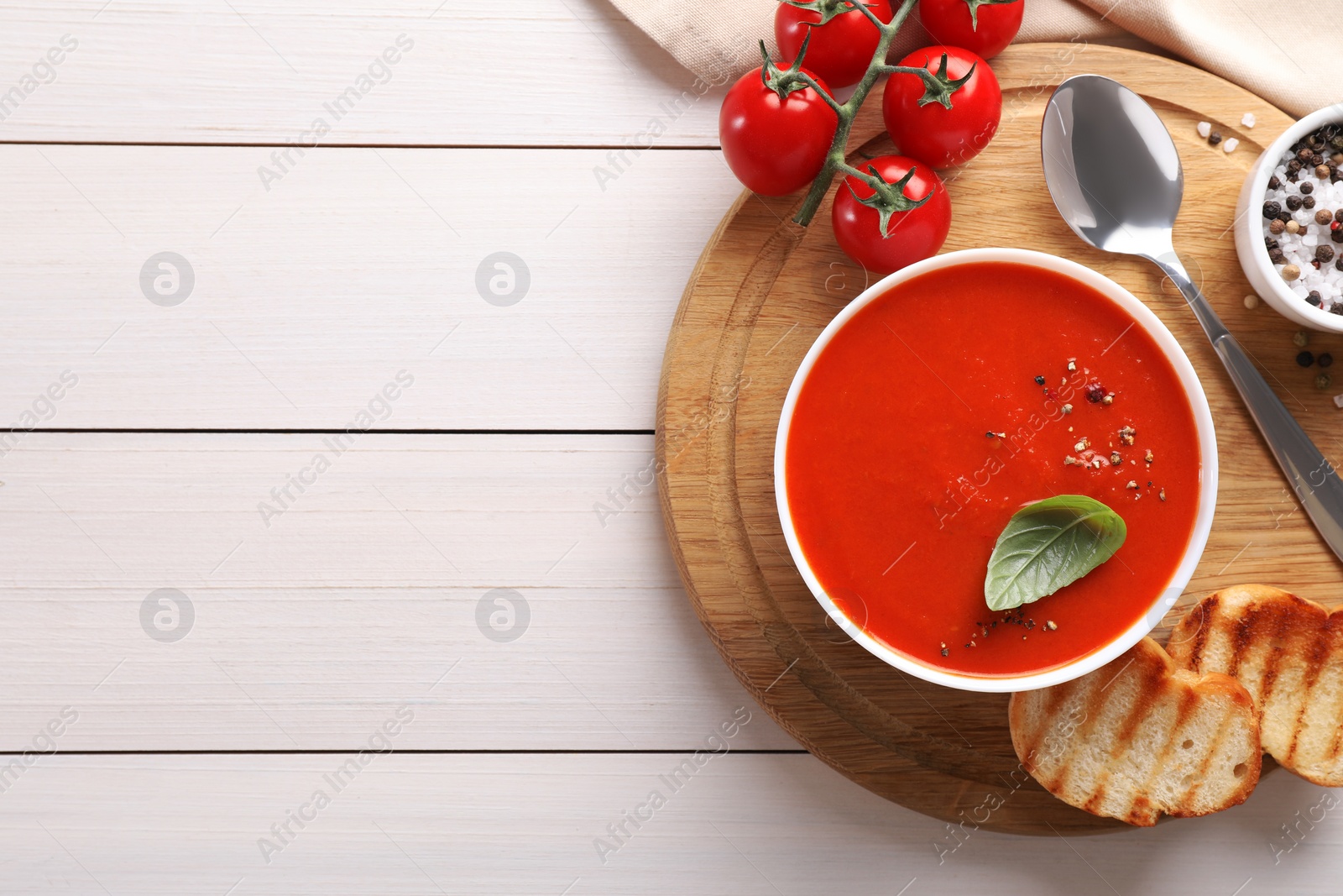 Photo of Delicious tomato soup served on white wooden table, flat lay. Space for text