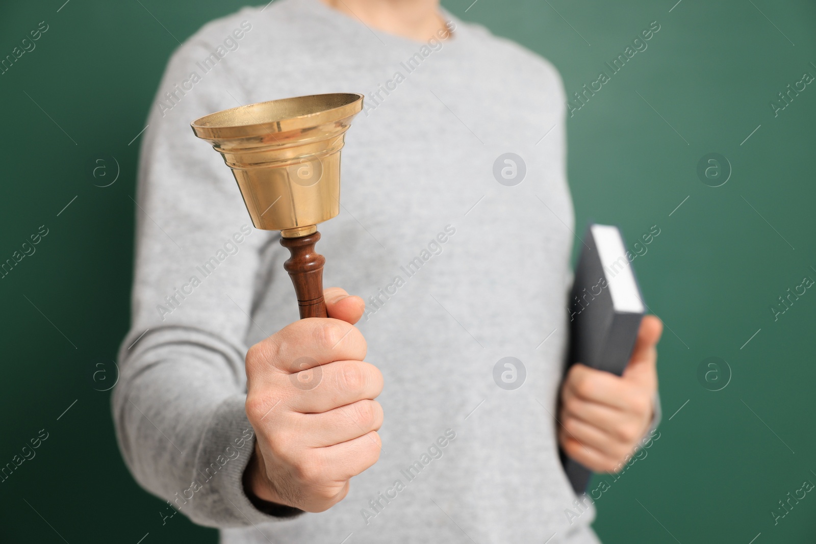 Photo of Teacher with school bell near chalkboard, closeup