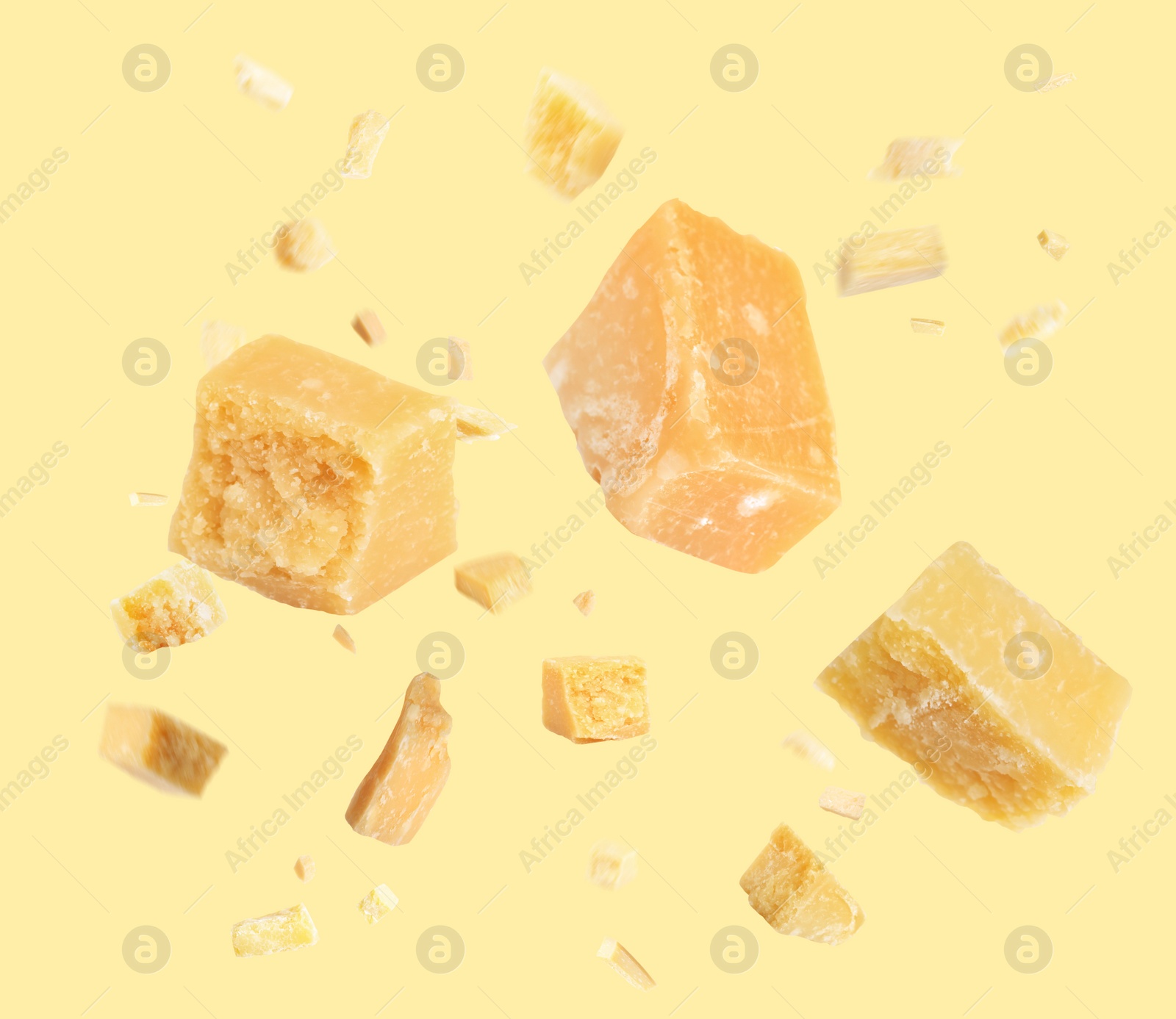 Image of Pieces of delicious parmesan cheese flying on yellow background