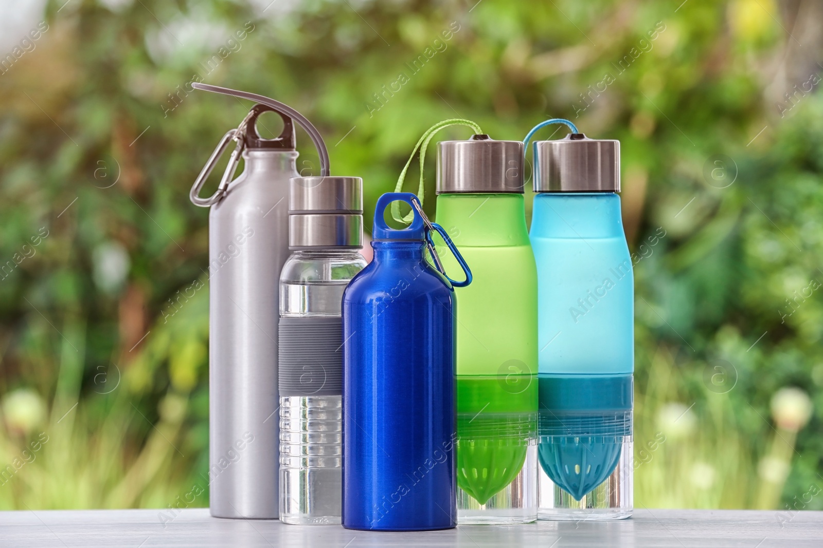 Photo of Sports water bottles on table against blurred background