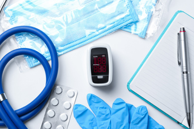 Photo of Flat lay composition with modern fingertip pulse oximeter and medical items on white background