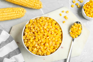 Delicious canned corn in bowl on marble table, flat lay