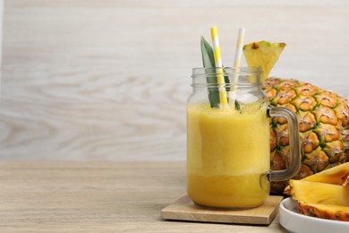 Photo of Tasty pineapple smoothie and fruit on wooden table. Space for text
