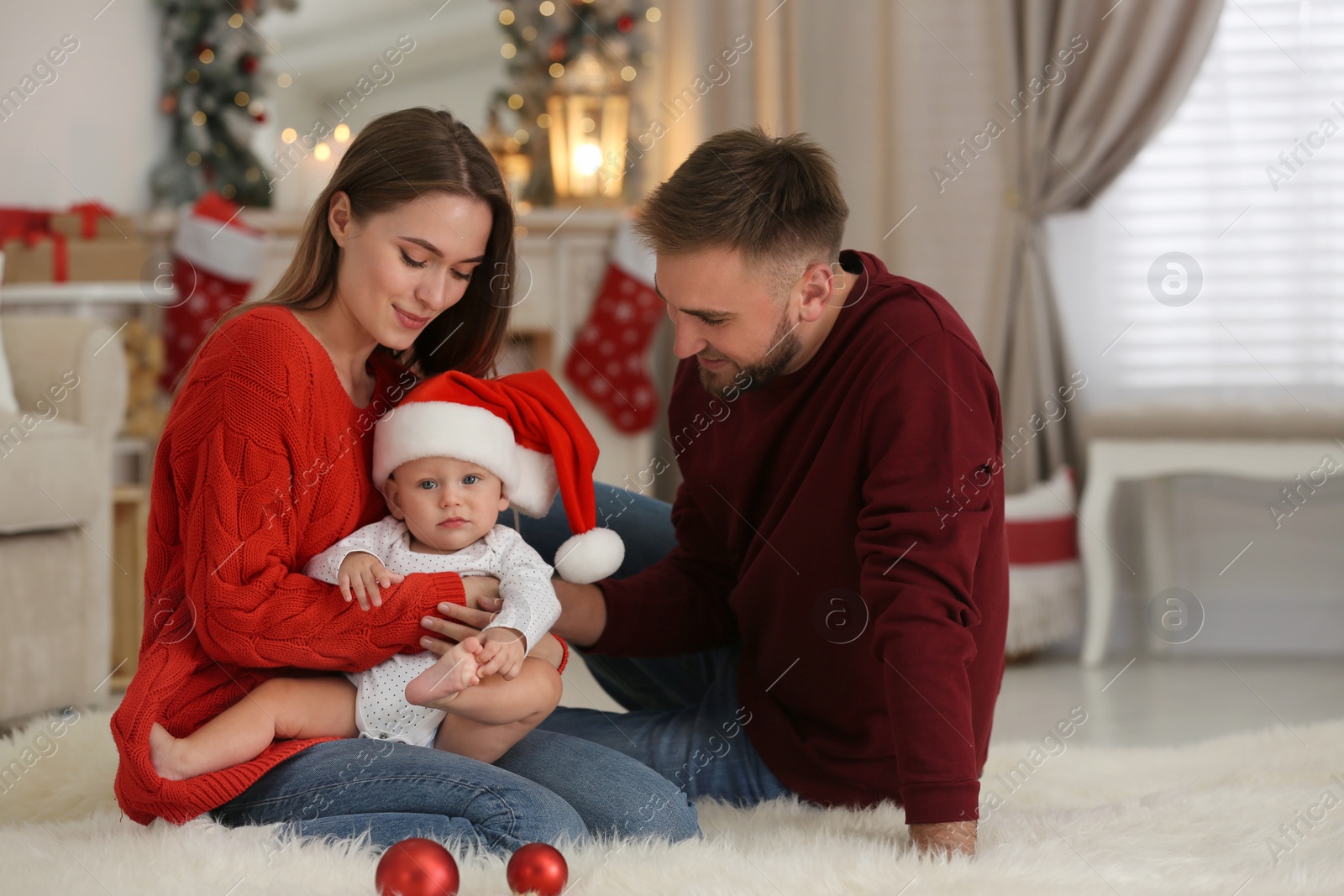 Photo of Happy family with cute baby in room decorated for Christmas holiday