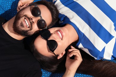Photo of Beautiful smiling woman and handsome man in sunglasses on blue floor covering outdoors, above view