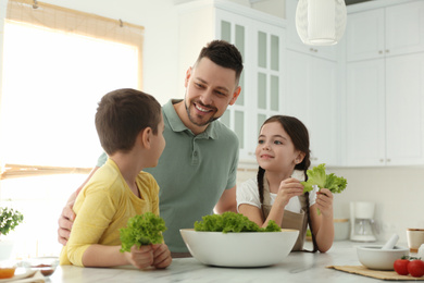 Happy family cooking salad together in kitchen