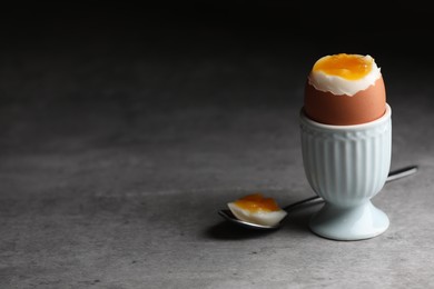 Photo of Cup with fresh soft boiled egg on grey table, space for text