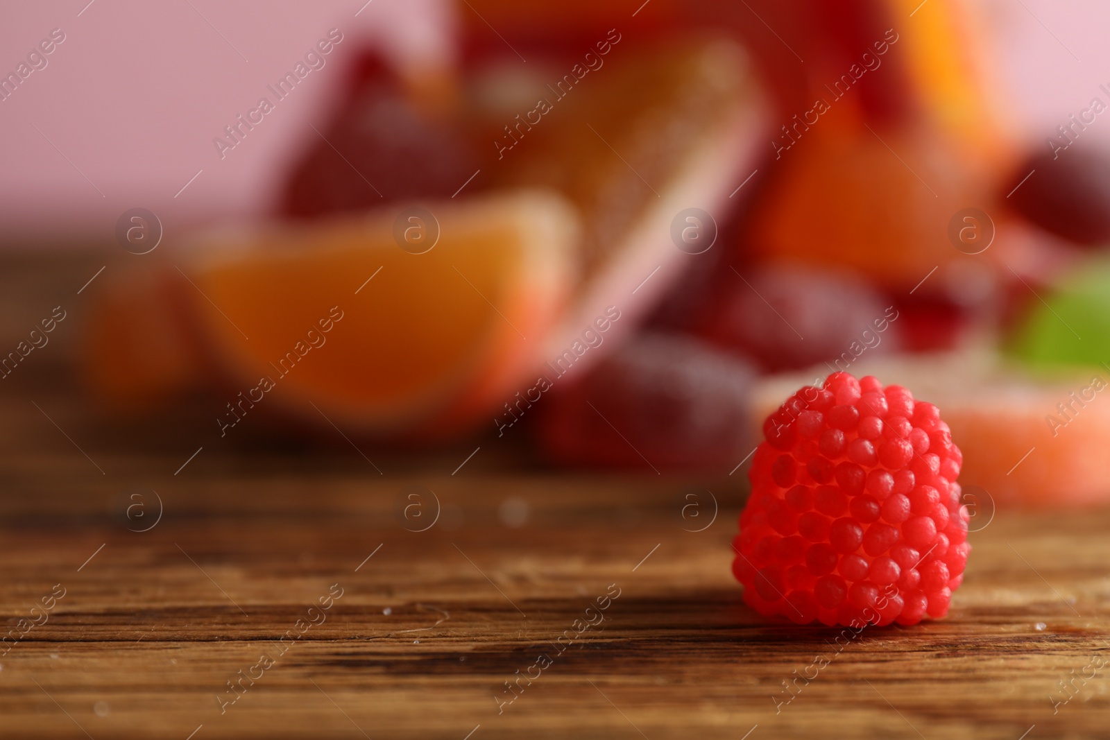 Photo of Delicious jelly candy on wooden table, closeup. Space for text