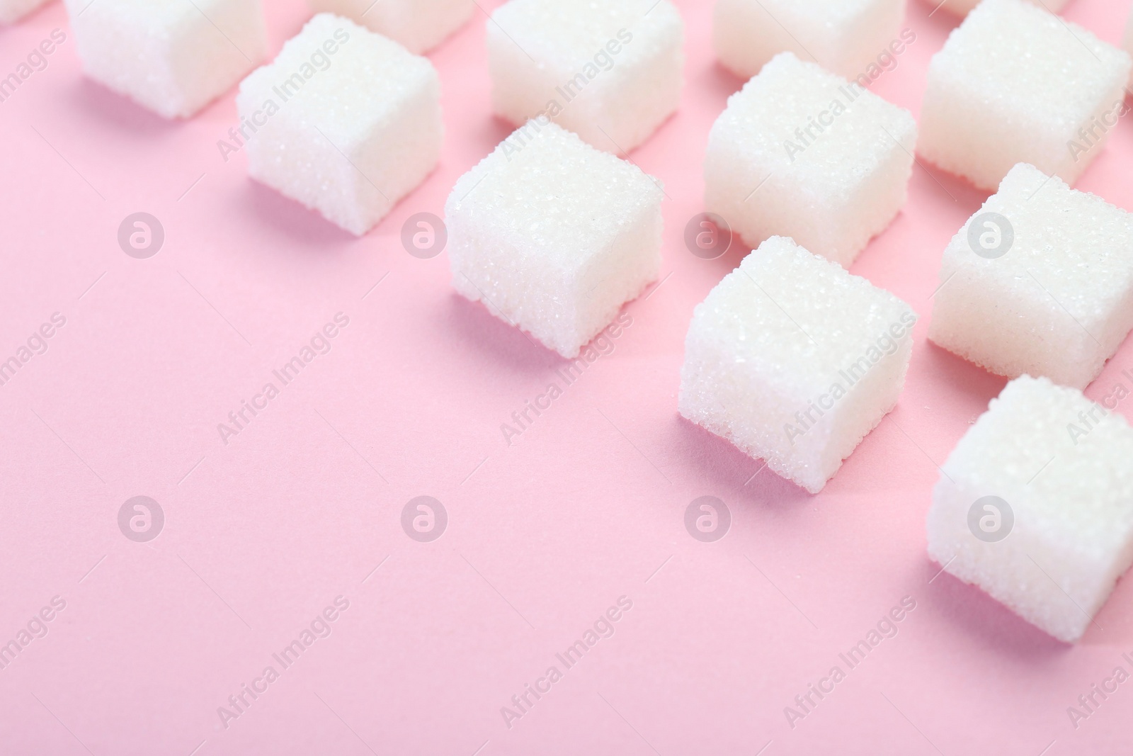 Photo of White sugar cubes on pink background, closeup. Space for text