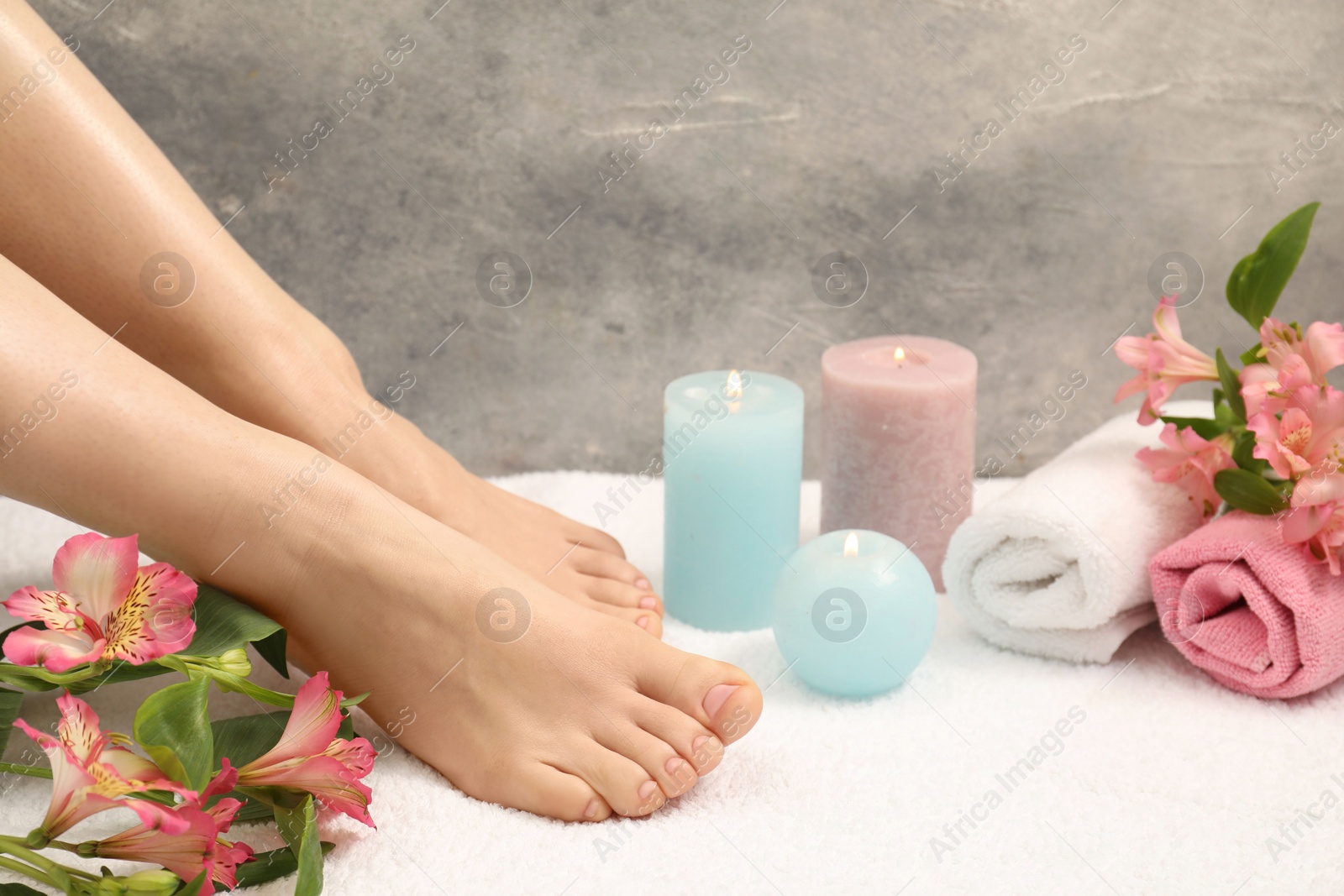 Photo of Woman with neat toenails after pedicure procedure on white terry towel, closeup