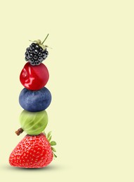 Stack of different fresh tasty berries and cherry on honeydew color background, space for text