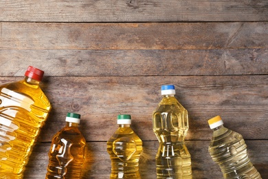 Bottles of oil and space for text on wooden background, top view