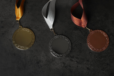 Gold, silver and bronze medals on grey stone background, flat lay. Space for design