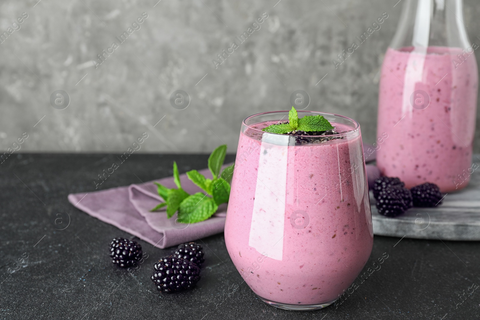 Photo of Delicious blackberry smoothie in glassware on black table