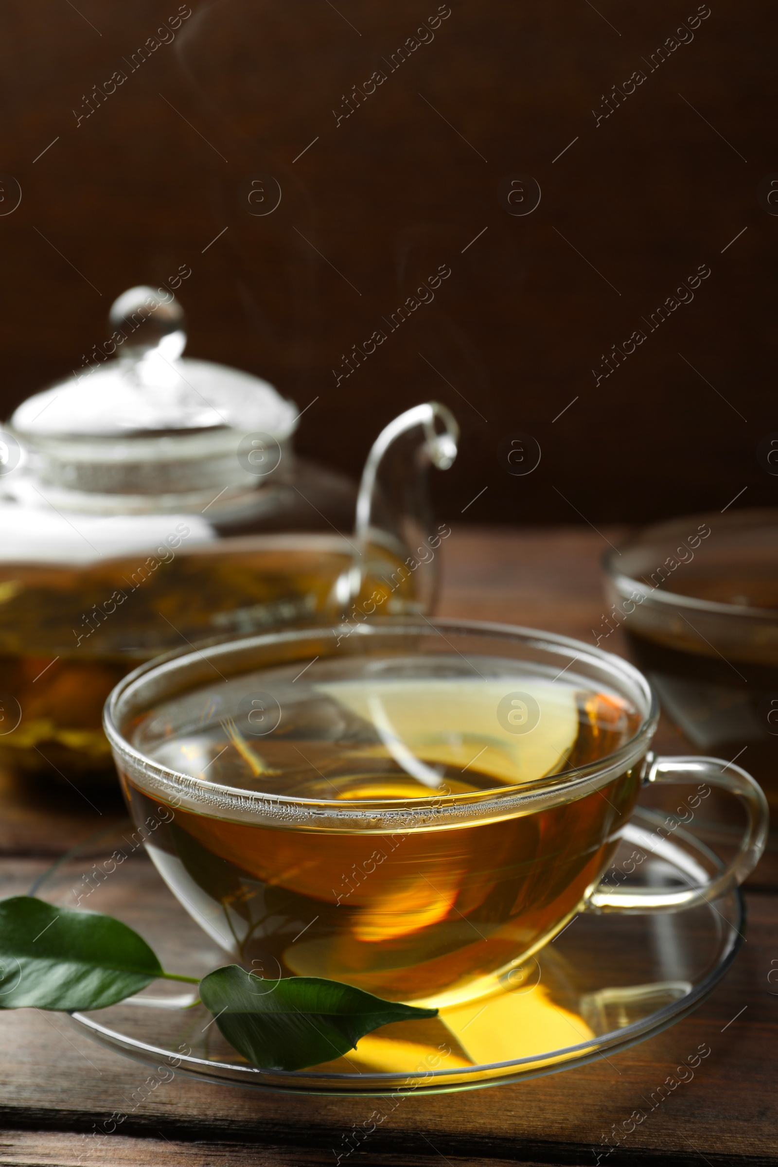 Photo of Fresh green tea in glass cups, leaves and teapot on wooden table